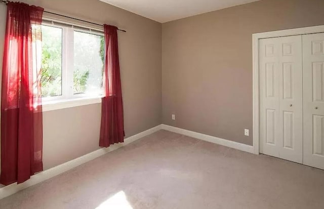unfurnished bedroom with light carpet, baseboards, and a closet