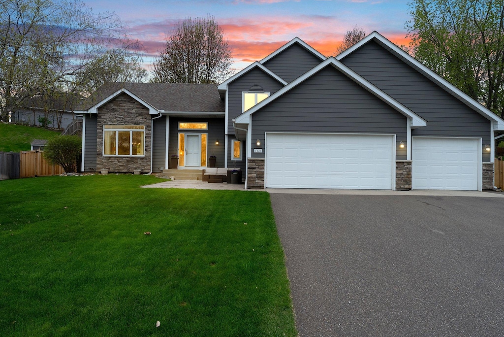 craftsman-style home with stone siding, aphalt driveway, a front yard, and fence