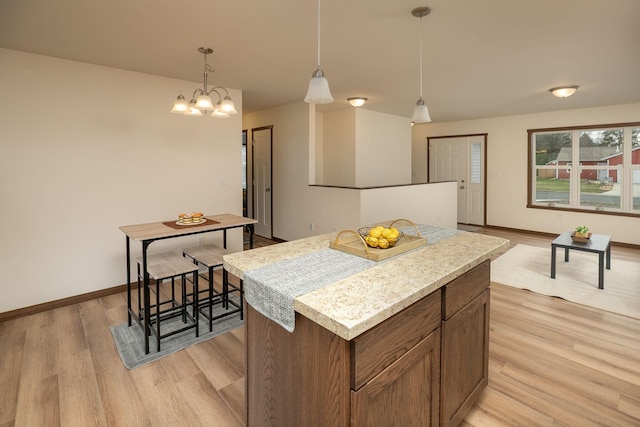 231 Julia St, Claremont, MN 55924 - kitchen with light wood finished floors, a center island, a notable chandelier, pendant lighting, and light countertops