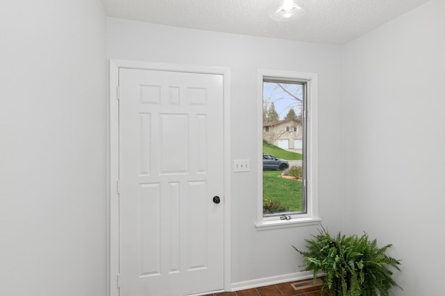 entryway featuring baseboards, dark wood-style floors, a textured ceiling, and visible vents