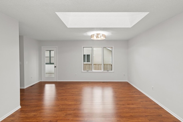 empty room featuring baseboards, wood finished floors, and a skylight