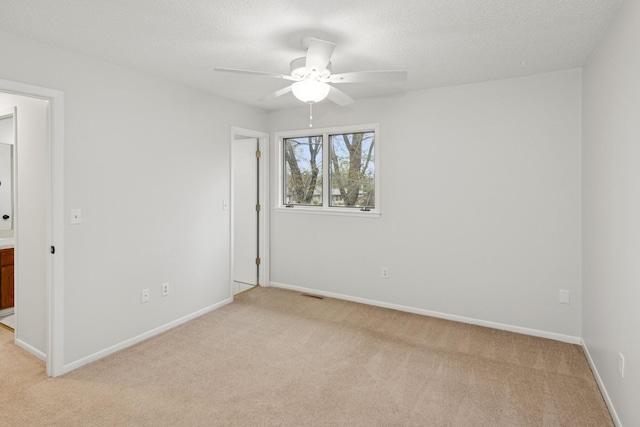 unfurnished room featuring baseboards, a ceiling fan, visible vents, and light carpet