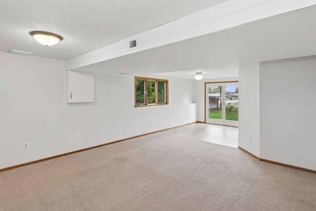 unfurnished room featuring carpet flooring, a textured ceiling, baseboards, and visible vents