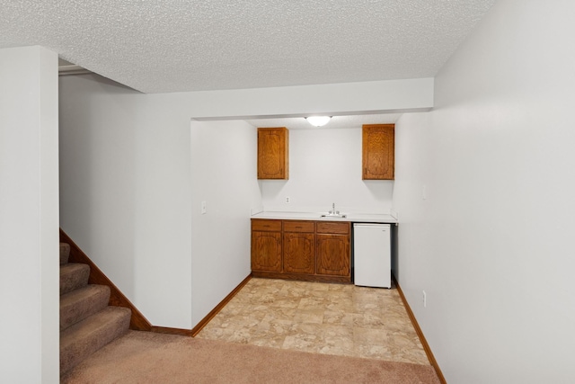 bar with baseboards, a textured ceiling, wet bar, and dishwasher