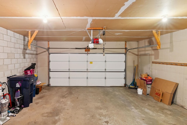 garage featuring a garage door opener and concrete block wall