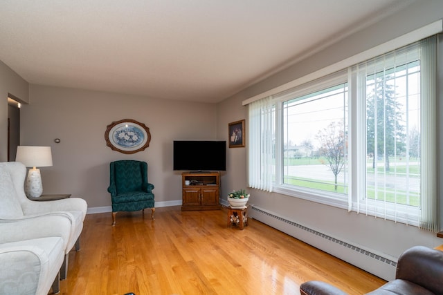 1001 Alexander St, Crookston, MN 56716 - living room featuring baseboards, a baseboard heating unit, light wood-type flooring, and a wealth of natural light