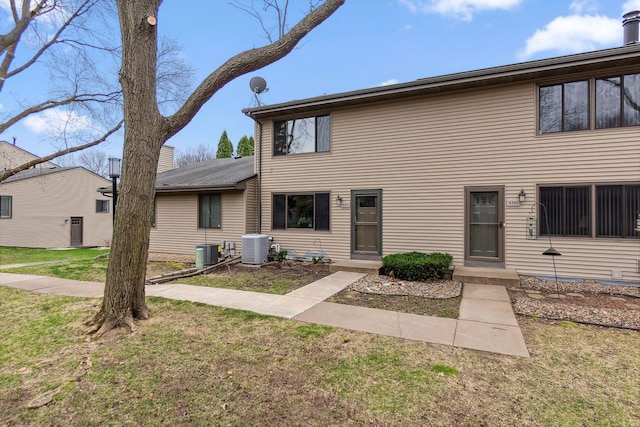 view of front of house with a front lawn and central AC