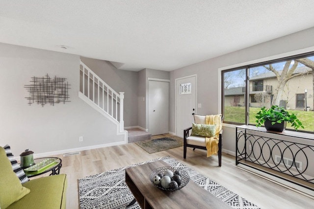 living area featuring baseboards, stairs, wood finished floors, and visible vents