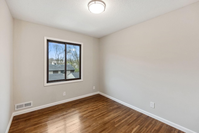 unfurnished room with visible vents, baseboards, and dark wood-style floors