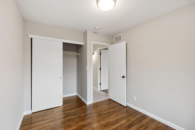 unfurnished bedroom with baseboards, visible vents, wood finished floors, and a closet
