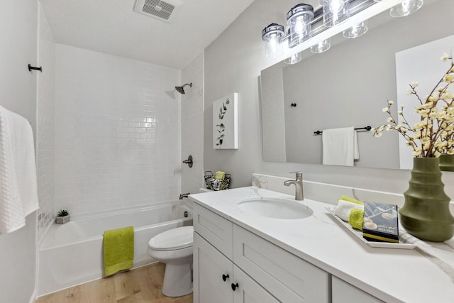 bathroom featuring visible vents, vanity, wood finished floors, toilet, and  shower combination