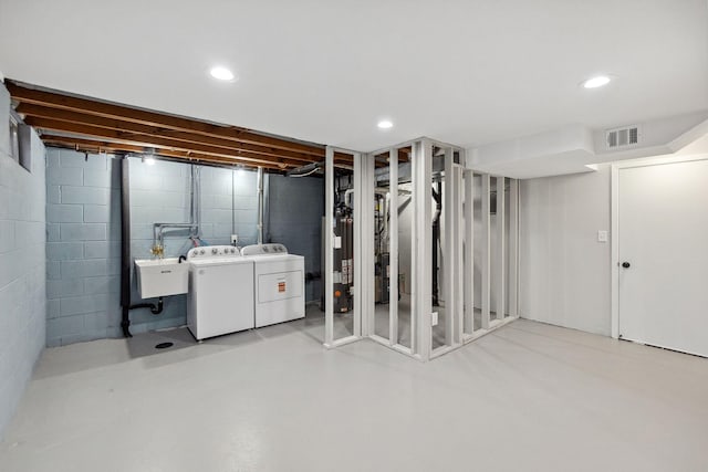 below grade area featuring washing machine and clothes dryer, a sink, water heater, recessed lighting, and visible vents