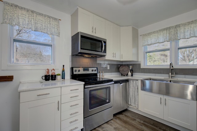 kitchen featuring a sink, decorative backsplash, stainless steel appliances, light countertops, and white cabinets