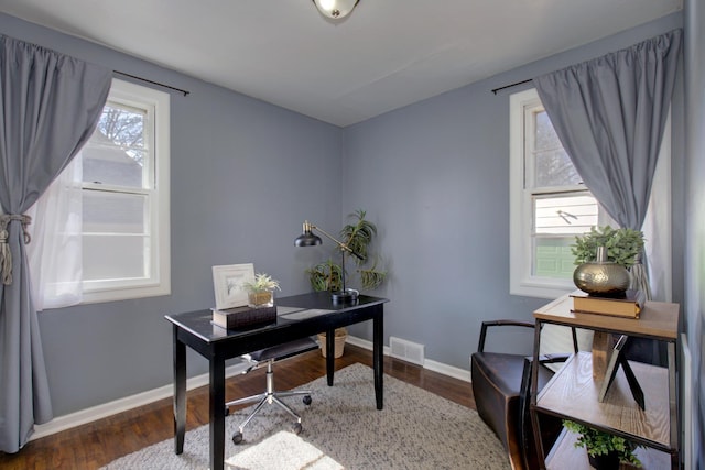 office area with dark wood-type flooring, visible vents, and baseboards