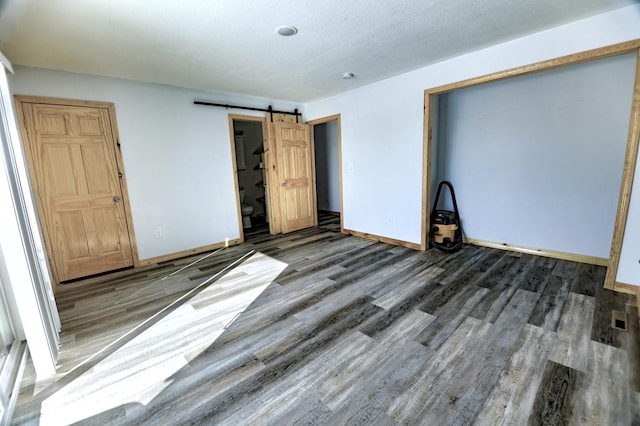 41634 Long Lake Rd, Ottertail, MN 56571 - unfurnished bedroom featuring wood finished floors, baseboards, and a barn door