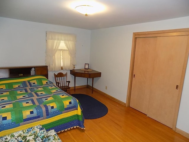 bedroom with wood finished floors, a closet, and baseboards