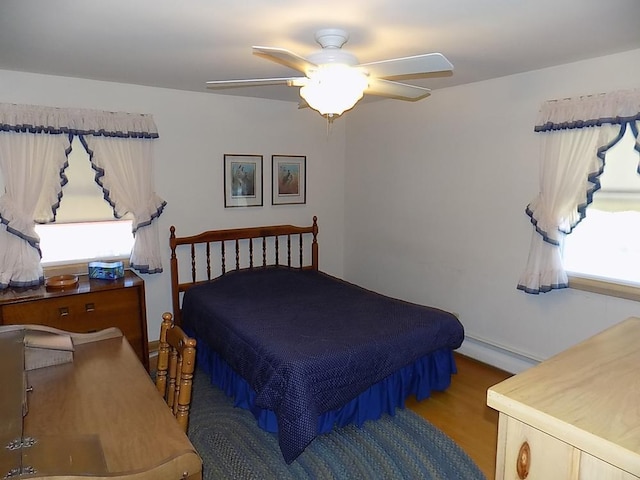 bedroom featuring a baseboard heating unit, ceiling fan, and baseboards