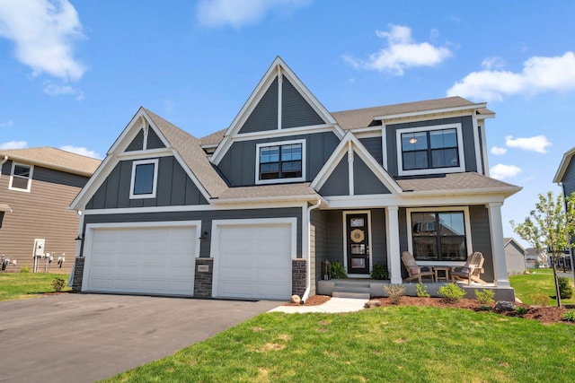 craftsman house with an attached garage, aphalt driveway, board and batten siding, a front yard, and a porch