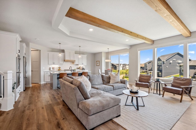 living room with a residential view, baseboards, beamed ceiling, light wood-style floors, and recessed lighting