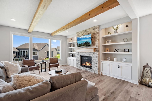 living room featuring light wood finished floors, a fireplace, baseboards, and beamed ceiling