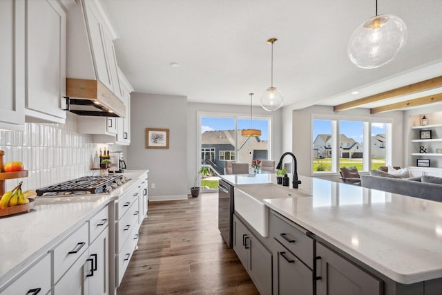 kitchen featuring a sink, stainless steel appliances, open floor plan, backsplash, and dark wood-style floors
