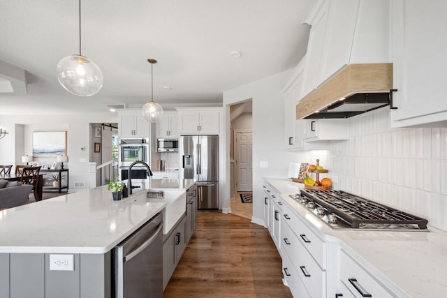 kitchen with light stone countertops, a sink, white cabinetry, tasteful backsplash, and appliances with stainless steel finishes