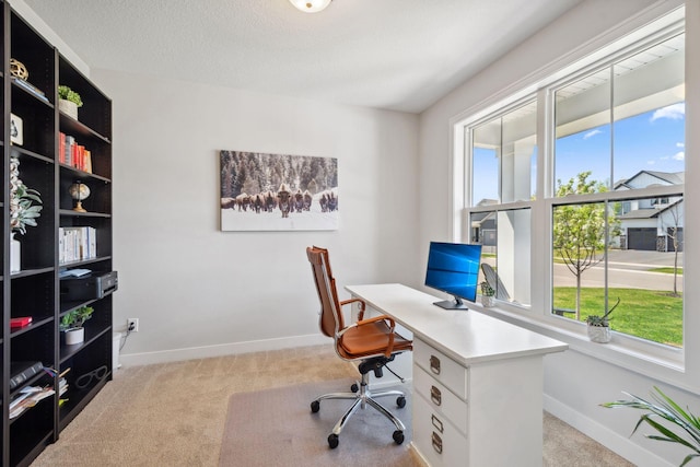 office space with light carpet, baseboards, and a healthy amount of sunlight