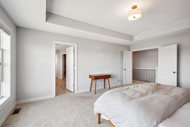 bedroom featuring visible vents, baseboards, and light carpet