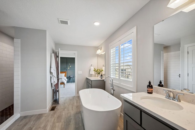 full bathroom featuring a sink, a freestanding tub, visible vents, and wood finished floors