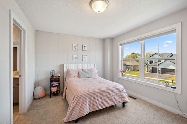 bedroom with baseboards, visible vents, and light colored carpet