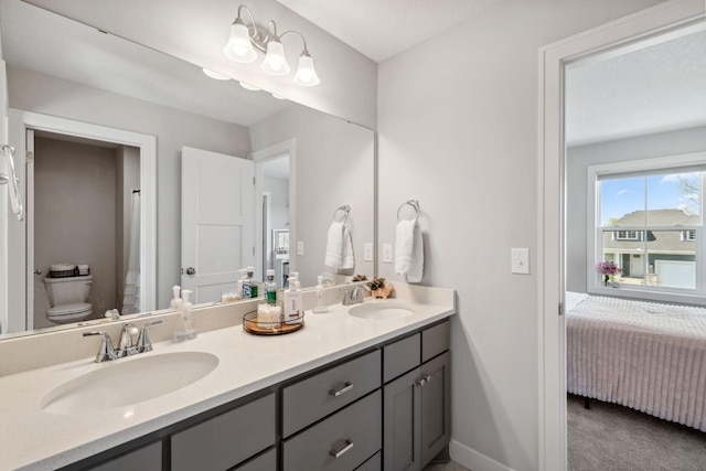 ensuite bathroom with a sink, double vanity, toilet, and connected bathroom