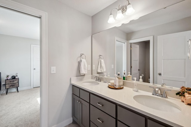 bathroom featuring a sink, double vanity, toilet, and baseboards