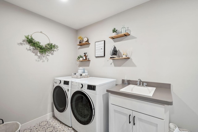 clothes washing area featuring baseboards, cabinet space, a sink, and washer and clothes dryer
