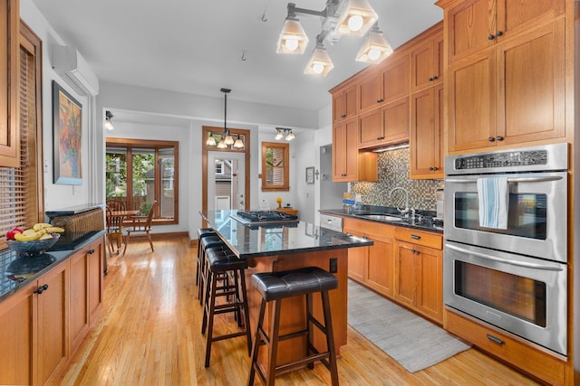 904 Lincoln Ave, Saint Paul, MN 55105 - kitchen featuring appliances with stainless steel finishes, light wood finished floors, decorative backsplash, and a kitchen island