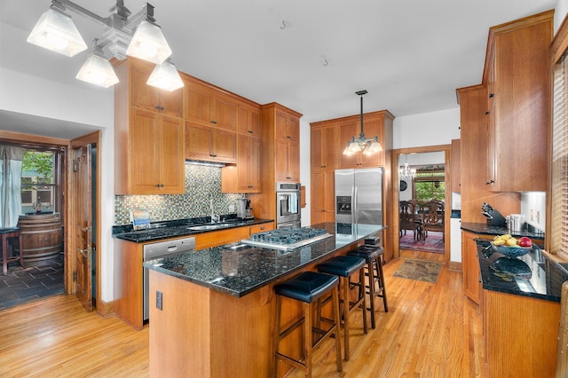 904 Lincoln Ave, Saint Paul, MN 55105 - kitchen featuring stainless steel appliances, light wood-style flooring, decorative backsplash, a kitchen island, and brown cabinetry