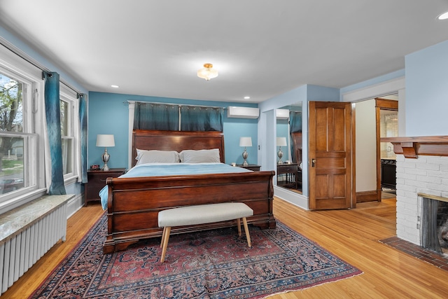 904 Lincoln Ave, Saint Paul, MN 55105 - bedroom with radiator heating unit, light wood-style floors, an AC wall unit, a fireplace, and recessed lighting