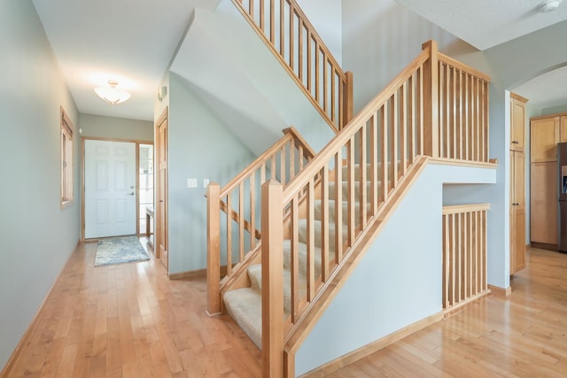 stairs featuring arched walkways, baseboards, and hardwood / wood-style floors