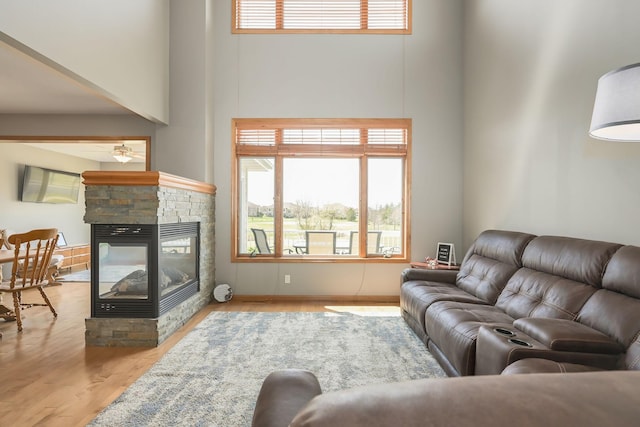 living area with a healthy amount of sunlight, a high ceiling, a fireplace, and ceiling fan
