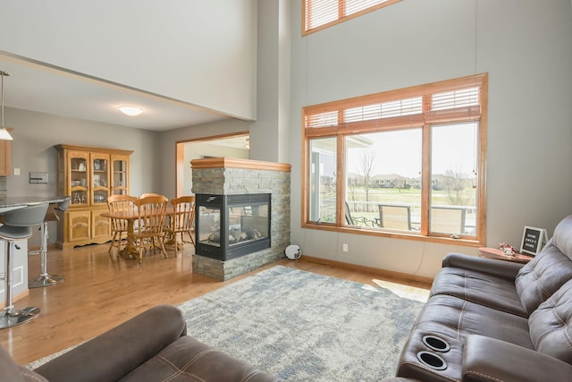 living area featuring wood finished floors, a high ceiling, and a fireplace