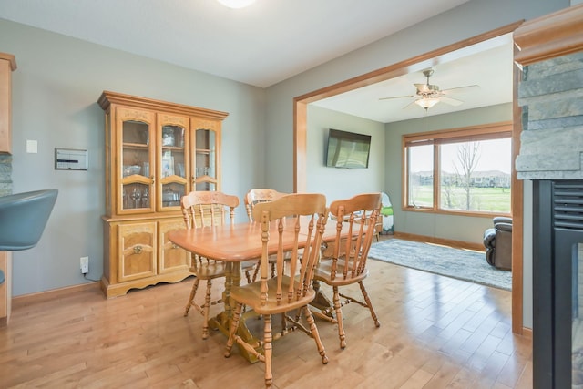 dining room featuring baseboards, light wood-style flooring, and ceiling fan