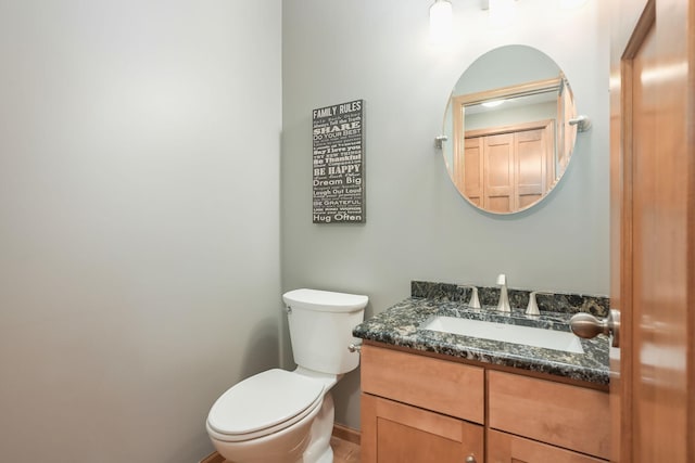 half bath with vanity, baseboards, and toilet
