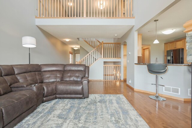 living area featuring baseboards, a high ceiling, visible vents, and wood finished floors