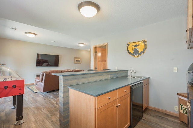 kitchen featuring fridge, wood finished floors, a sink, baseboards, and a peninsula