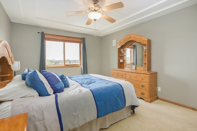bedroom featuring a ceiling fan, baseboards, light colored carpet, and a raised ceiling