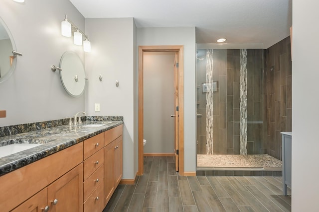 bathroom featuring wood tiled floor, a stall shower, a sink, toilet, and recessed lighting