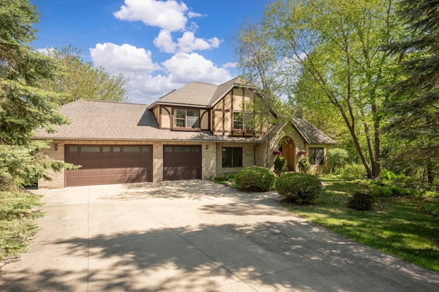 tudor house featuring concrete driveway, brick siding, and a garage