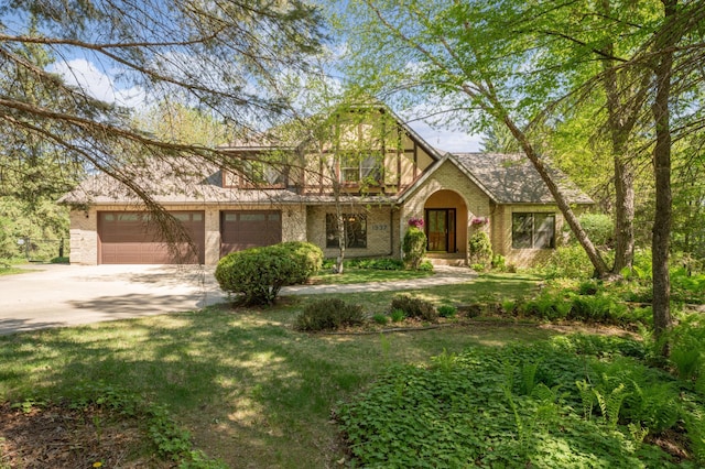 tudor-style house with brick siding, concrete driveway, and a front yard