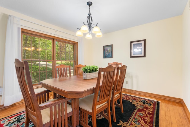 dining space featuring a chandelier, light wood-type flooring, and baseboards