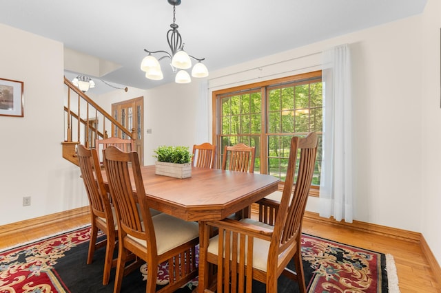 dining space featuring a chandelier, wood finished floors, baseboards, and stairway