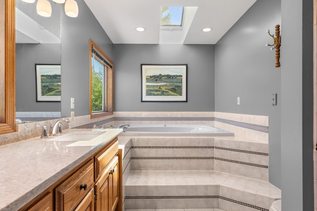 bathroom with a skylight, vanity, a garden tub, and recessed lighting